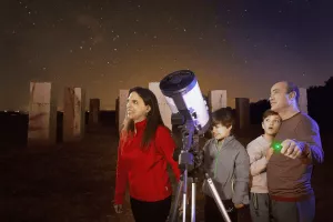 familia de cinco personas con un telescopio observando el cielo